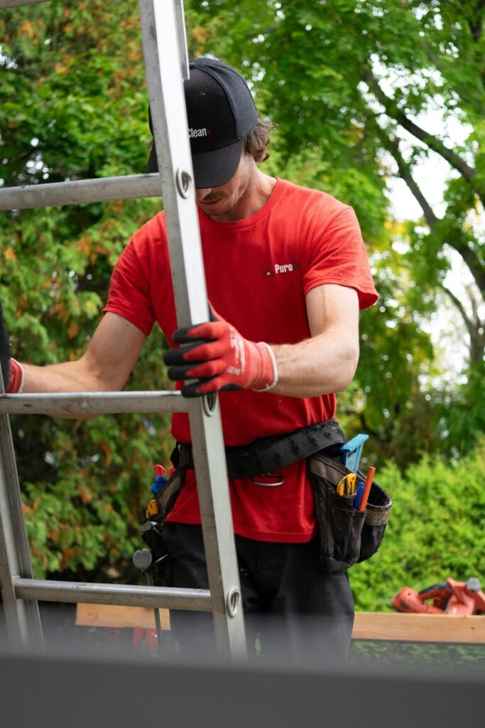 worker in green foliage A worder holding a ladder surrounded by green foliage.